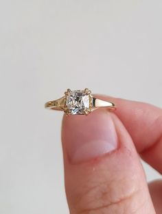 a hand holding a gold ring with a white diamond in it's middle finger