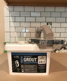 a white bucket filled with grout sitting on top of a counter