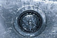 a metal sink with water droplets on the bottom and round holes in the drain head