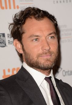 a man in a suit and tie posing for a photo on the red carpet at an event