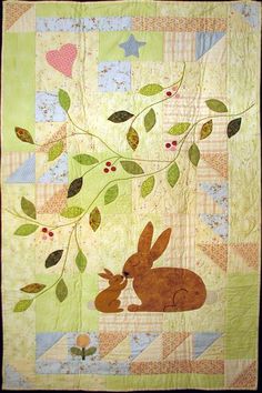 a quilted wall hanging with a rabbit and leaves