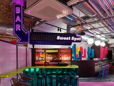 an indoor bar with neon lights and colorful chairs in front of the bar sign that says sweet spot