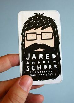 a hand holding up a business card with a man's face and glasses on it