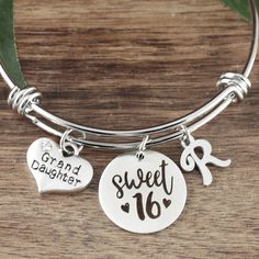 a close up of a bracelet on a wooden table with two charms and a leaf