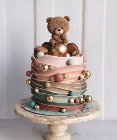 a teddy bear sitting on top of a multi layered cake