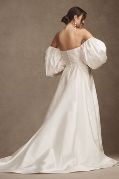 a woman in a white wedding dress with her back to the camera, looking down