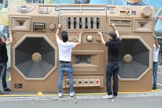 two men standing in front of an old radio on the side of the road with their hands up