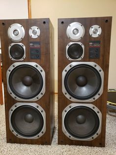 two speakers sitting side by side on top of a carpeted floor next to each other