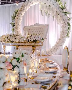 a table set up for a wedding with white flowers and greenery