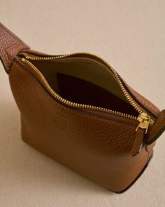 The Mason 12 is designed to be scrunched in the hand at an evening soiree, or tossed into a bigger bag to keep essentials accessible. Acorn Tumbled Grain Calfskin leather lends itself to a soft, slouchy silhouette, while signature Mark Cross collar studs bring a touch of elevation to a casual shape. Lined in soft lambskin suede in natural beige. Formal Brown Bag With Grained Texture, Luxury Brown Bag With Pebbled Texture, Luxury Brown Bags With Pebbled Texture, Everyday Calf Leather Bag With Grained Texture, Everyday Bags In Calf Leather With Grained Texture, Evening Leather Shoulder Bag With Grained Texture, Luxury Grained Texture Shoulder Bag For Everyday, Luxury Everyday Bag With Grained Texture, Evening Shoulder Bag With Grained Leather