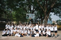 a group of young people posing for a photo in front of a basketball hoop with their hands up