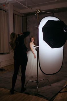 a woman is standing in front of a light and another person is taking a photo