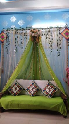 a green bed sitting in front of a blue wall with flowers and curtains on it