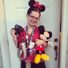 a woman holding two mickey mouses in her hands while standing next to a door