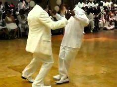 two men in white suits dancing on a dance floor