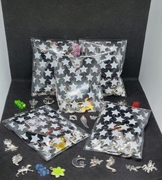 five bags filled with assorted charms on top of a black table next to each other