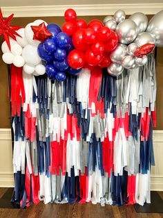 red, white and blue balloons are hanging on the wall