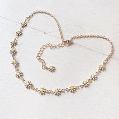 Wander wild and free with this cheery, playful, choker necklace. Flower-filled daisy blooms set in white and yellow enamel are paired alongside a shimmery satin gold-plated chain, allowing for this adjustable accessory to give you the versatility to express your boho vibes however you please. Rock it as a necklace or wrap it up for a bracelet - it's totally up to you! Perfect for any occasion, showcase your care-free spirited style with this flirty, fun accessory and let your inner flower child Dainty Gold Jewelry For Spring, Spring Adjustable Gold Chain Jewelry, Spring Choker Jewelry, Gold Jewelry With Adjustable Chain For Spring, Dainty Adjustable Spring Jewelry, Adjustable White Flower Necklace For Summer, Dainty Adjustable Jewelry For Spring, Adjustable Dainty Spring Jewelry, Dainty Spring Jewelry With Flower Charm