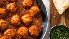 meatballs and sauce in a pan on a wooden table next to tortilla chips