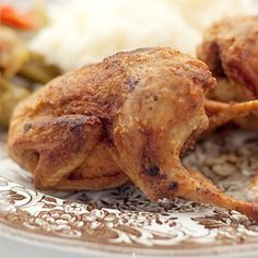 two pieces of chicken on a plate with rice and green beans