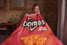 a girl is holding up a giant pizza blanket with the word doritos on it