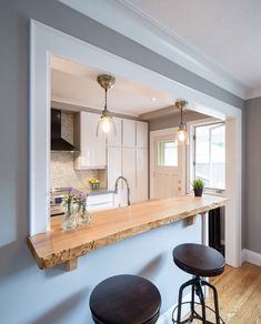 an empty kitchen with two stools in front of the counter and bar top area