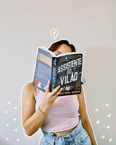 a woman is reading a book while wearing denim shorts and a pink tank top with her head in the air