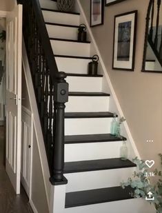 the stairs are painted black and white in this entryway with pictures on the wall