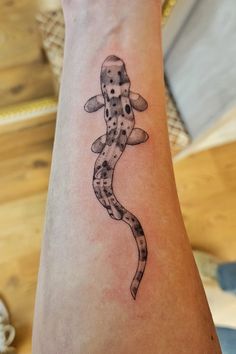 a tattoo on the arm of a person with a gecko in it's arms