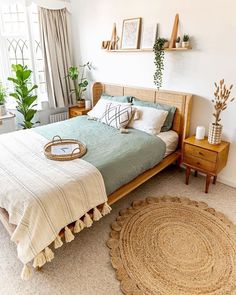 a bed room with a neatly made bed and lots of plants on the windowsill