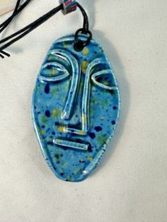 a blue face is hanging from a cord on a white surface with other items in the background