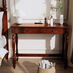 a wooden table topped with books and a lamp next to a bed in a room