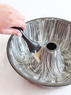 a person using a brush to clean a metal bowl