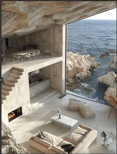 a living room with an ocean view and stairs leading up to the top floor is shown