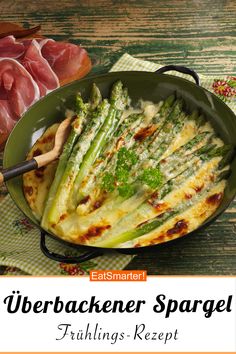 a pan filled with asparagus and meat on top of a table