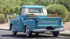 an old blue chevrolet pickup truck driving down the street