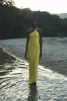 a woman in a yellow dress standing in the water