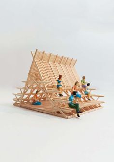 miniature people are building a wooden structure together