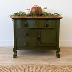 a green dresser with two pumpkins on top