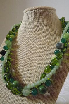 "Cracked green agate, jade, cats' eye, and faceted stones are gorgeous in this fresh design. This multi strand necklace is 19\" and is finished with a silver hook clasp. The design can also be worn untwisted.  All orders come in a beautiful gift box ready for giving along with a special \"thank you\" gift. Thank you for sharing my love of jewelry." Green Double Strand Beaded Necklace, Green Double Strand Necklace With Faceted Beads, Green Multi-strand Beaded Necklace With Natural Stones, Green Agate Jewelry With Faceted Beads, Green Onyx Necklace With Faceted Beads, Adjustable Green Double Strand Necklace, Green Jade Necklaces With Faceted Beads, Green Crystal Necklaces With Faceted Beads, Green Jade Necklace With Faceted Beads