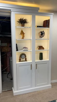 a white bookcase filled with lots of books next to a wall mounted clock and other items