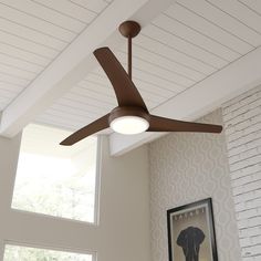 a ceiling fan in a living room next to a window with a painting on the wall