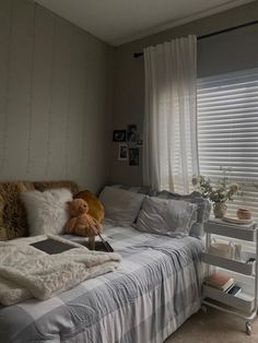 a bed room with a neatly made bed and a teddy bear sitting on top of it