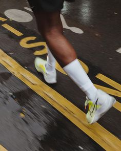 a person in white socks and black shorts is running on the street with yellow lines