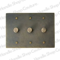 an antique brass plate with four knobs and three holes on the front, in different sizes