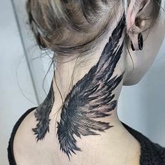 the back of a woman's neck is covered in black ink with an angel wing tattoo on it