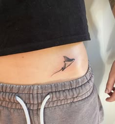 a woman's stomach with a small bird tattoo on the side of her belly