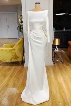 a white dress is on display in a room with wooden floors and yellow couches