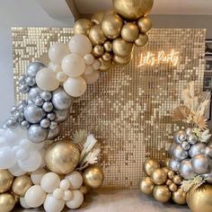 some balloons are hanging from the ceiling in front of gold and silver decorations on display