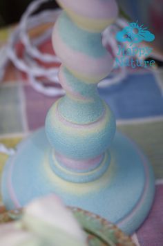 a blue and pink vase sitting on top of a table next to a white ribbon